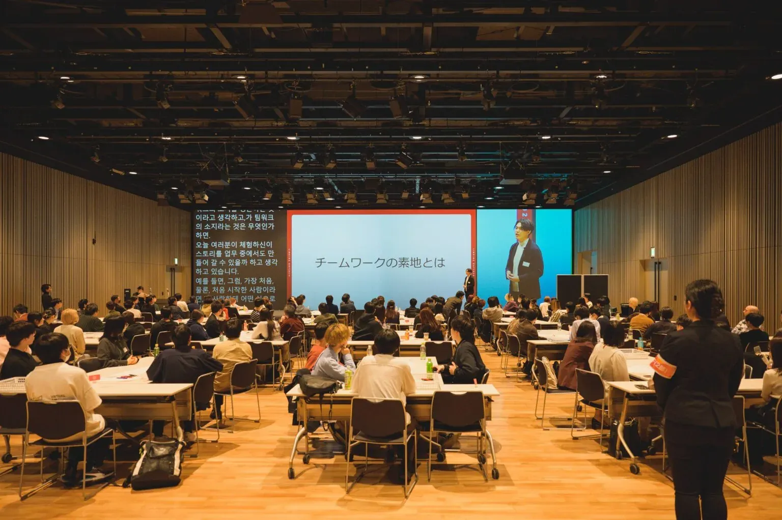 大きな会場でチームごとにゲームに取り組む会社総会の様子