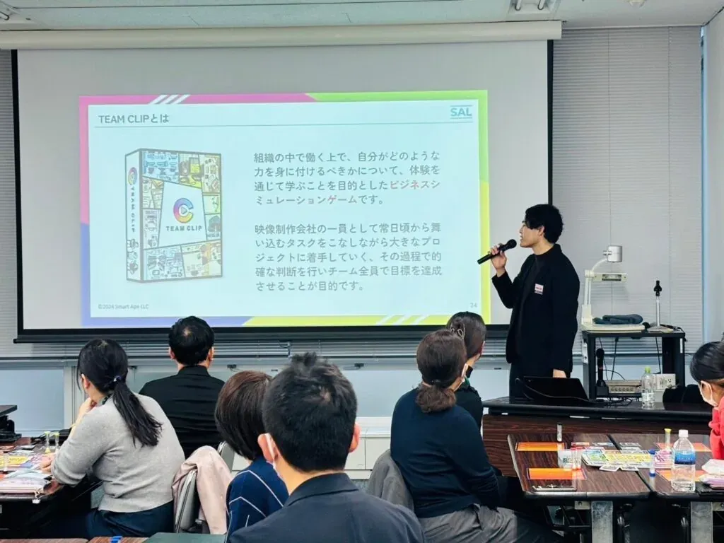 スクリーンに映した TEAM CLIP の説明を聞く経営企画部の皆さん